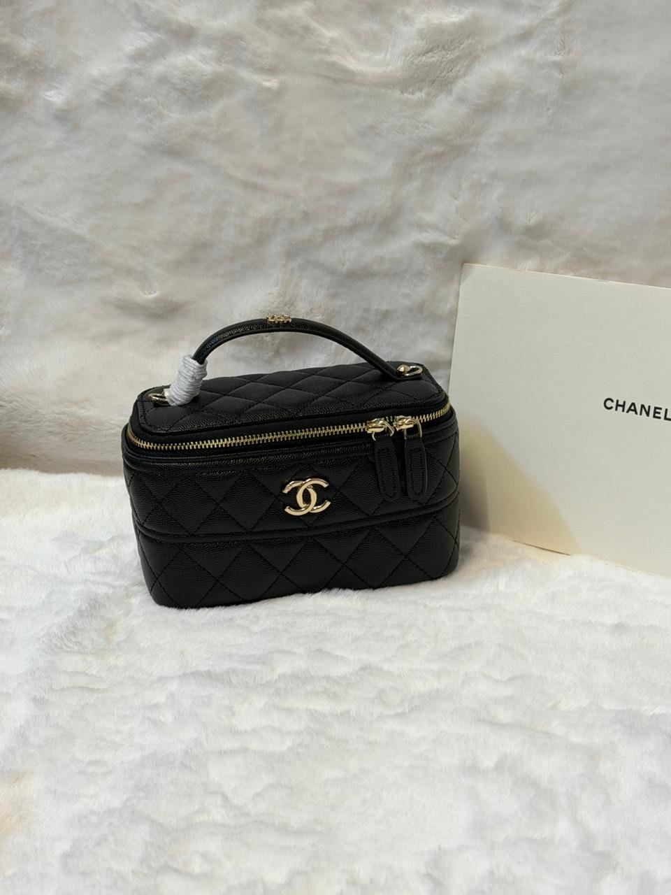 Chanel black vanity case bag is a versatile accessory crafted from durable caviar leather, featuring the iconic CC logo, a zip closure, and a chain shoulder strap for both day and evening use.